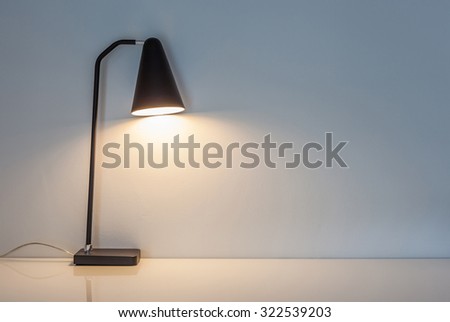 The modern desk lamp illuminate on the wall background. (left the right space for text)