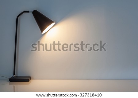 The modern desk lamp illuminate on the wall background. (left the right space for text)