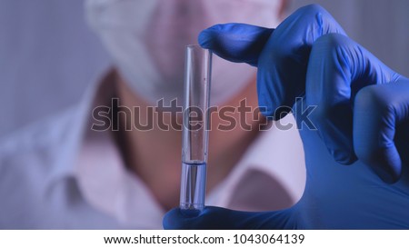 Lab work, Doctor holds a test tube, in a medical mask and glasses, takes the test from a test tube in blue rubber gloves, analysis, blood, DNA, test tube stand.