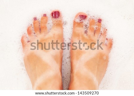 Funny tanned legs in a bubble bath