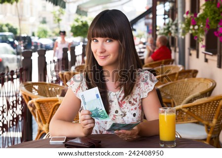 Happy woman in a cafe counting money