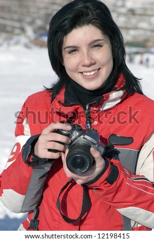 Attractive woman in sport wear holding a camera, winter outdoors (series sport, mountains, extreme, horses, teenagers)
