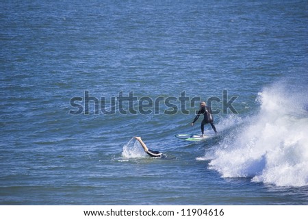 one surfer going under the wave and one on the wave with plenty of copy space