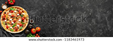 Italian pizza and pizza cooking ingredients on black concrete background. Tomatoes on vine, mozzarella, black olives, herbs and spices. Copy space for text. Banner composition