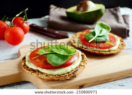 Avocado toast with tomato and spinach on whole grain round flat bread