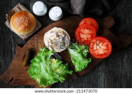 Making chicken sandwich: homemade hamburger buns, tomatoes, green salad, shredded chicken, mustard, pickles and light yogurt sauce