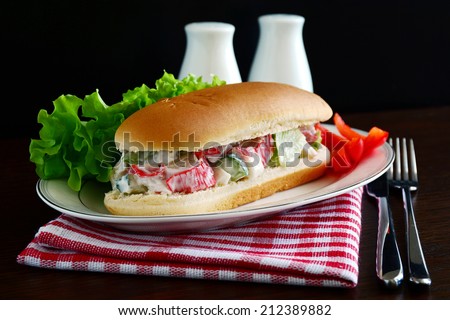 Sandwich roll with crab meat, fresh cucumber, red bell pepper and iceberg lettuce leaves in light yogurt sauce