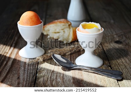 Breakfast image: soft boiled egg in white egg cup and ciabatta on dark wooden table