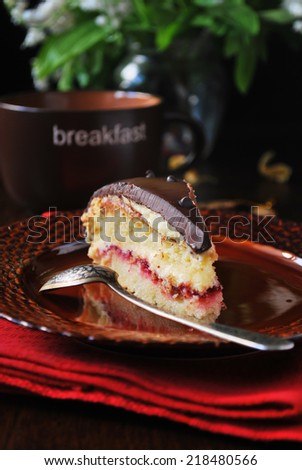 Victoria\'s sponge cake with strawberry jam filling and chocolate ganache on brown plate, vertical image
