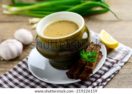 Creamy garlic soup on bowl served with rye garlic bread sticks, horizontal view