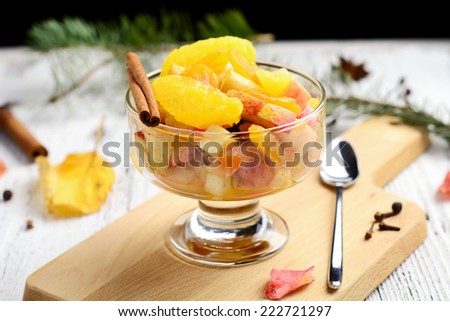 Fresh fruit salad with orange, apple, raisins, peach and cinnamon in dessert cup, close up