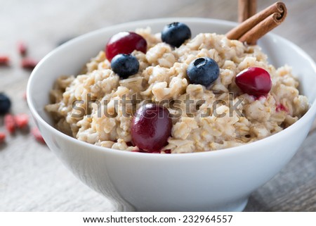 Breakfast oatmeal porridge with cinnamon, cranberries and blueberries, front view, selective focus