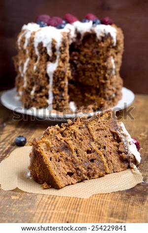 Piece of chocolate gingerbread cake on parchment paper on rustic wooden table, vertical close up image