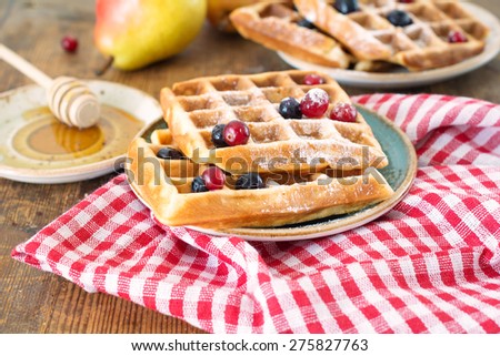 Homemade belgian waffles with powdered sugar, honey and berries on rustic wooden table, breakfast set