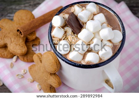 Mug with hot chocolate topped with mini marshmallows and gingerbread man cookies