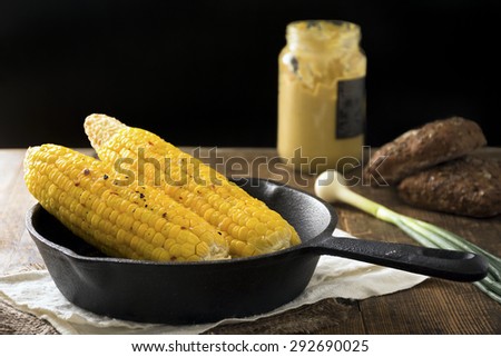 Food still life: roasted corn on the cob in iron skillet