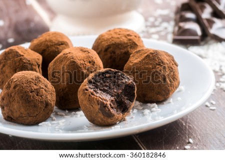 Homemade healthy vegan chocolate truffles with dates, coconut flakes and rolled oats served on white plate