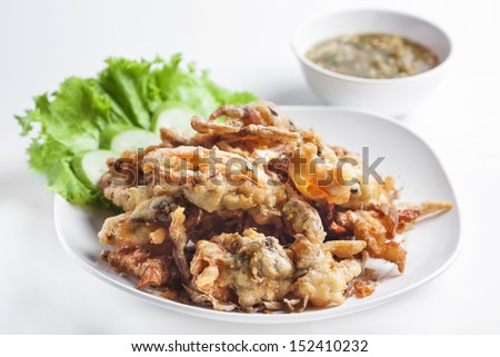 Batter-fried soft shell crab in dish on white background.