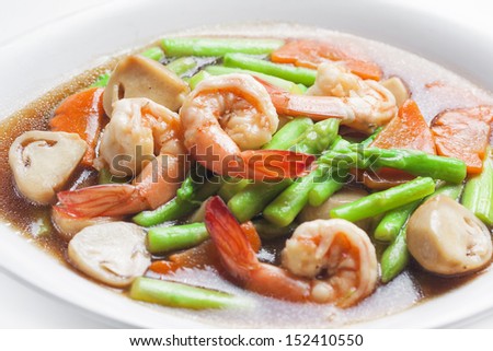 Stir-fried mixed vegetables with prawns in dish on white background.