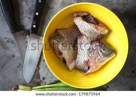 Preparing fish for food in yellow bowl.