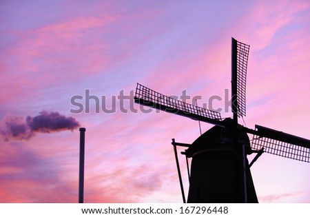 Dutch windmill and smoking chimney at sunset
