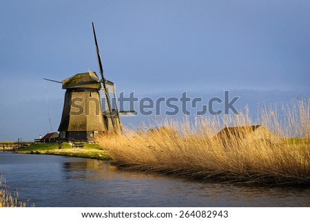 Two old water mills beside a canal of the Eilandspolder in evening light, The Netherlands
