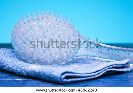 Bathroom scene with body brush massager covered by water drops and blue towel.