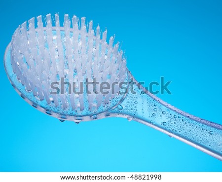 Bathroom scene with body brush massager covered by water drops and set against blue background.