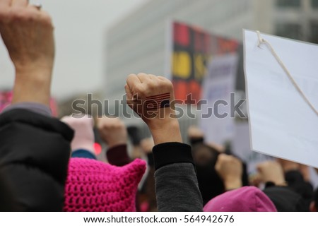 Woman\'s fist with US flag raised in the air at Women\'s March in Washington DC
