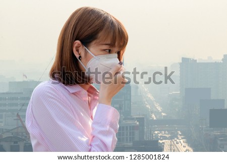Asian woman wearing the N95 Respiratory Protection Mask against air pollution at road and traffic in Bangkok, healthcare concept