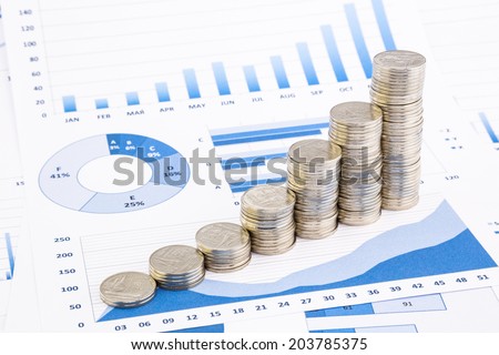 closeup stacks of Thai baht coins on blue graphs and charts background, money and financial concepts