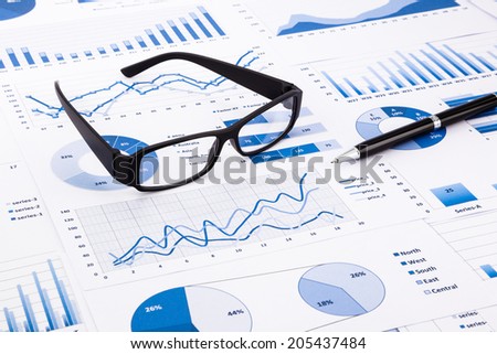 glasses and pen on blue charts, graphs, data and document background for financial and business concepts