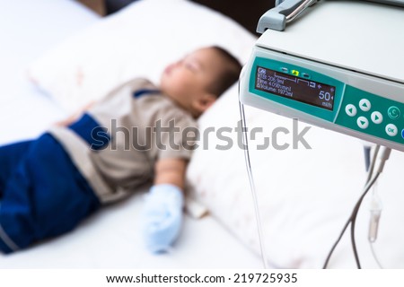 sick baby receiving intravenous therapy in hospital, focus on infusion pump