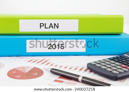 PLAN and 2015 words on labels with document binders, graphs and business reports