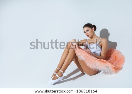ballerina in a tutu is sitting on the floor