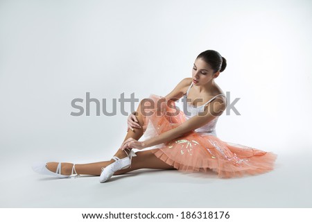 ballerina in a tutu is sitting on the floor
