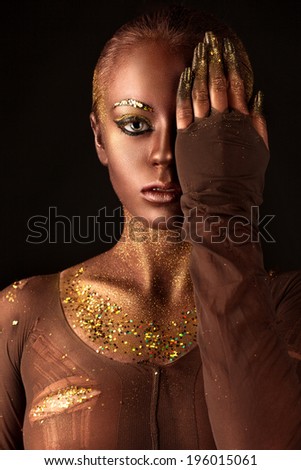and beautiful young woman with a beautiful visage and gold sequins on the body