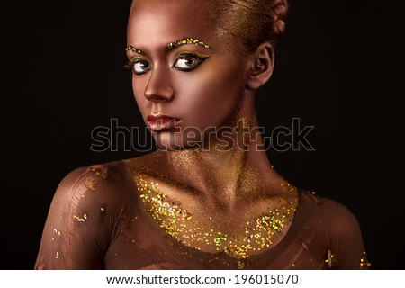 and beautiful young woman with a beautiful visage and gold sequins on the body