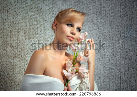 beautiful and well-groomed woman with a branch of orchid in the hands of