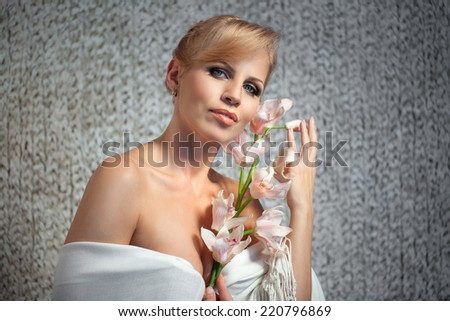 beautiful and well-groomed woman with a branch of orchid in the hands of