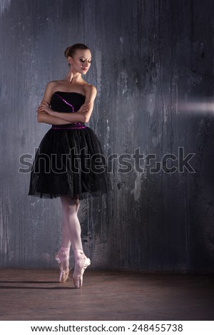 ballerina in black dress near the wall in the dark ballet slippers