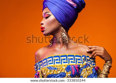 African woman in a bright dress on orange background