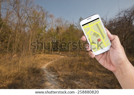 A man using Smartphone with a GPS map to find the way out of Forest.