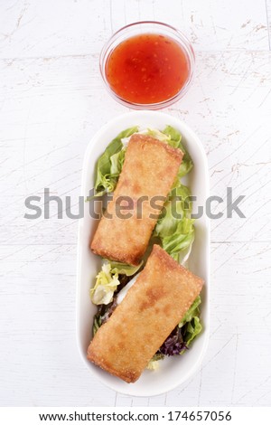 spring rolls with salad on a white plate and some sweet chili dipping sauce