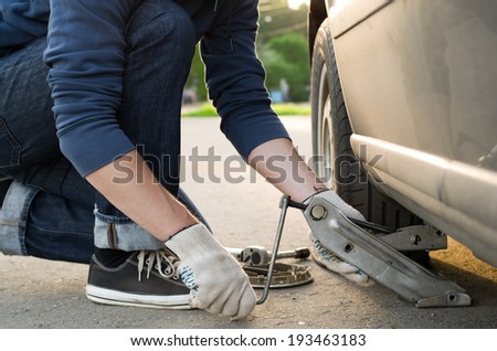 Man picks up a car jack to change a tire
