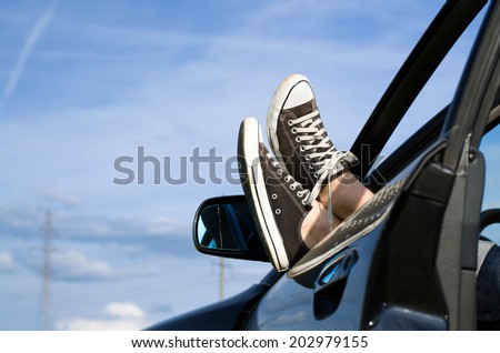 Car driver relaxing. Feet out of vehicle window.