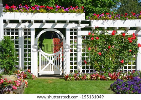 White garden gate and fence in colorful botanical garden