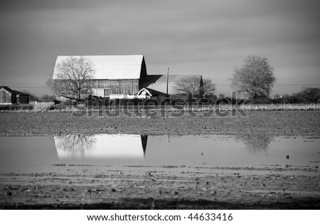 Black and white shot of barn on flooded farm land