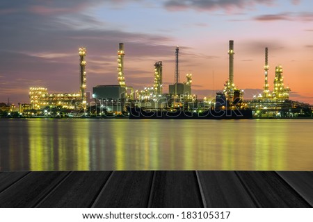 wood planks floor with Oil refinery plant at twilight background