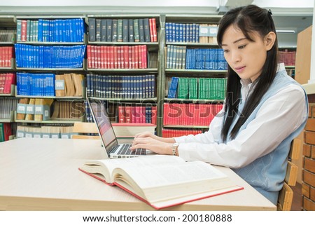 Asian student using laptop computer in university library